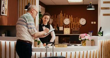 oud persoon ondertekening controleren in vormen Bij voorkant bureau, afwerking met registratie documenten met werknemer Bij vakantie toevlucht. toerist registreren Bij allemaal inclusief vijf ster hotel, gastvrijheid industrie. foto