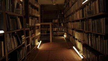 nacht bibliotheek met knippert lichten. voorraad filmmateriaal. gang met boekenkasten in nacht bibliotheek. knippert lichten in gangpad tussen boekenkasten van nacht bibliotheek foto