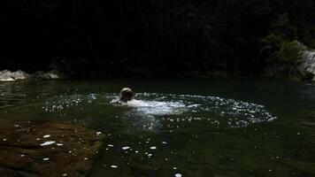 een jong jongen het baden in een berg rivier- zwembad. creatief. kind hebben pret in een zomer natuurlijk vijver. foto