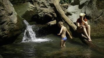 mam met jongen kind in tropisch waterval. creatief. familie van wandelaars Aan een zomer reis in oerwouden. foto