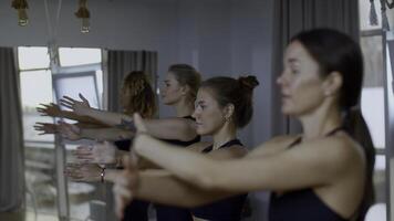 ontspannen sport- team staand gedurende groep opleiding in ruim studio. media. Dames adem diep en swinging hun handen, concept van yoga en ontspanning. foto