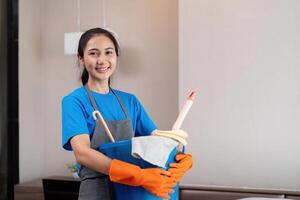 schoonmaak Product, en mand met vrouw Aziatisch personeel schoonmaak onderhoud in slaapkamer naar schoon bacterie Bij appartement. schoonmaakster of hulp in de huishouding met houder naar werk in kamer foto