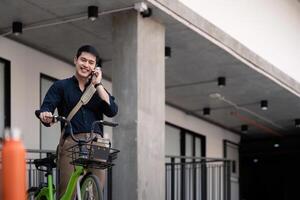 zakenman en fiets in stad naar werk met eco vriendelijk vervoer. fiets en gelukkig zakenman professioneel praten, sprekend en telefoon discussie terwijl Aan in stedelijk straat foto