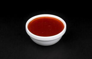heet chili saus in kom geïsoleerd Aan zwart achtergrond foto