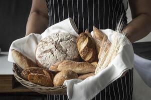 een persoon Holding een mand vol van brood foto