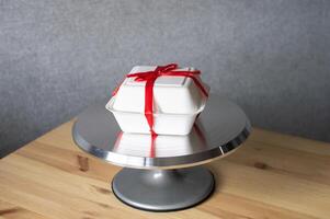 gebakje metaal draaitafel voor cakes Aan houten tafel met taart bento verpakking foto