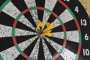 drie geel darts gericht in de centrum van een dartbord foto