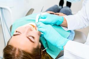 vrouw tandarts controle omhoog geduldig tanden met een beugel Bij tandheelkundig kliniek kantoor. geneesmiddel, tandheelkunde concept. tandheelkundig apparatuur. dichtbij omhoog. foto