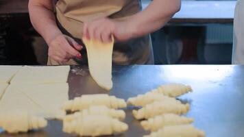 vrouwen handen rollen croissants in een bakkerij. maken croissantjes. de concept van productie van bakkerij producten. dichtbij omhoog foto