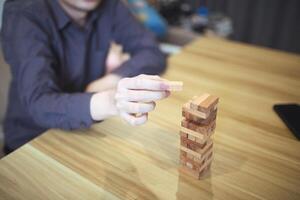 bedrijf strategie concept met handen spelen een houten blok toren spel, symboliseert risico en stabiliteit. planning risico beheer foto