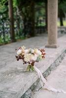 bruiloft boeket van bloemen staat Aan een steen grens in de buurt een kolom in de tuin foto
