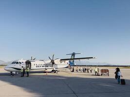 Podgorica, Montenegro - 16 augustus 2023. passagiers wachtrij naar bord de vlak Aan de landingsbaan foto