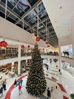 Podgorica, Montenegro - 25 december 2022. hoog versierd Kerstmis boom staat in de lobby van de winkelcentrum foto