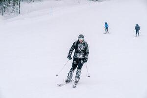 met sneeuw bedekt skiër in stofbril ritten naar beneden de berg helling foto