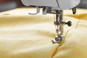 modern naaien machine met geel velours- kleding stof dichtbij omhoog foto