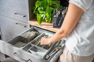 huisvrouw handen opruimen omhoog bestek na vaatwasser machine. vrouw netjes in elkaar zetten vork, lepel, mes accessoires voor opslagruimte organisatie . hoog kwaliteit foto