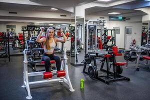 jong sport vrouw vervelend sport slijtage aan het doen oefening met geschiktheid uitrusting Bij Sportschool, ze oefening voor sterk en mooi zo gezond. hoog kwaliteit foto