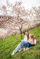 jong vrouw met weinig dochter in een bloeiend roze en wit tuin petrin in Praag, voorjaar tijd in Europa. hoog kwaliteit foto