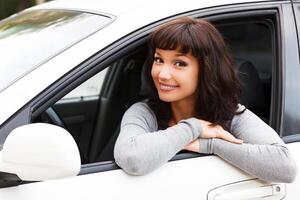 gelukkig eigenaar van een nieuw auto. jong mooi vrouw bestuurder glimlachen naar u foto