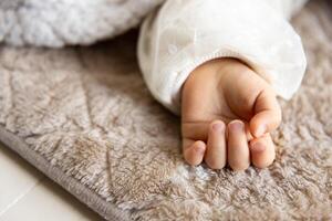 een links hand- van slapen Aziatisch baby Aan de tapijt foto