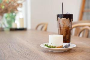 witte chocolade cheesecake met ijsmocca op houten tafel in café foto