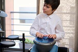 tiener- jongen musicus genieten van spelen de Afrikaanse etnisch percussie musical instrument trommel - djembé, bongo, tam tam. gelukkig tiener creëren de ritme van Afrikaanse muziek- bonzen etnisch trommel foto