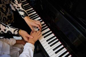 top visie handen van musicus pianist leraar maestro onderwijs een kind jongen de waar positie van vingers Aan piano sleutels terwijl het uitvoeren van musical samenstelling Aan groots pianoforte, gedurende muziek- piano les foto