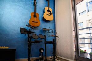 modern interieur van een muziek- studio Bij huis. akoestisch en elektrisch gitaren hangende Aan blauw kleur muur en trommel set. hobby's en vrije tijd. van muzikant kamer voor spelen en aan het leren muziek- foto
