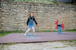 sportief kind meisje Toneelstukken hinkelen, duurt bochten jumping over- pleinen gemarkeerd Aan grond. kinderen en actief gezond levensstijl foto