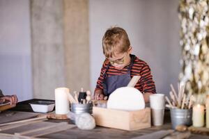 handgemaakt keramiek 5 jaar oud jongen met bril verkennen kunst foto