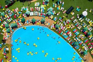 top visie van mensen ontspannende in de zwembad Aan geel opblaasbaar cirkels en zon bedden Aan de strand foto