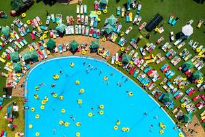 top visie van mensen ontspannende in de zwembad Aan geel opblaasbaar cirkels en zon bedden Aan de strand foto