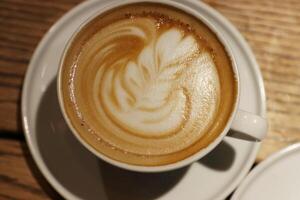 een kop van latte, cappuccino of espresso koffie met melk zetten Aan een hout tafel in cafe. room schuim Aan de top van kop van koffie. barista koffie latte kunst. top visie foto