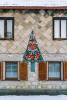 voelde Kerstmis boom met rood bogen en slingers blijft hangen Aan de facade van de huis foto