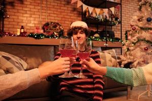close-up shot, geluk familie en vrienden vieren, heffen glazen en vrolijke glimlach met drankjes in de huiskamer, ingericht voor kerstfeest en nieuwjaarsdag. foto