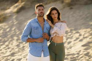 jong koppel staande op het zand van het strand foto