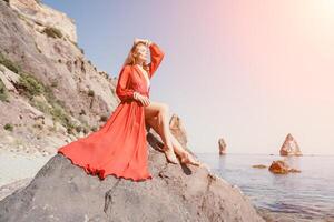 vrouw reizen zee. jong gelukkig vrouw in een lang rood jurk poseren Aan een strand in de buurt de zee Aan achtergrond van vulkanisch rotsen, Leuk vinden in IJsland, sharing reizen avontuur reis foto