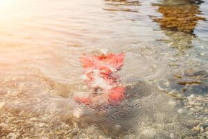 vrouw reizen zee. gelukkig toerist in rood jurk genieten nemen afbeelding buitenshuis voor herinneringen. vrouw reiziger poseren in zee strand, omringd door vulkanisch bergen, sharing reizen avontuur reis foto