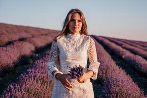vrouw lavendel veld. gelukkig zorgeloos vrouw in een wit jurk wandelen in een lavendel veld- en ruiken een lavendel boeket Aan zonsondergang. ideaal voor warm en inspirerend concepten in reislust en reizen. foto