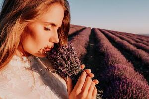 vrouw lavendel veld. gelukkig zorgeloos vrouw in een wit jurk wandelen in een lavendel veld- en ruiken een lavendel boeket Aan zonsondergang. ideaal voor warm en inspirerend concepten in reislust en reizen. foto