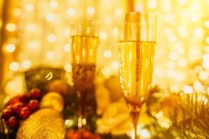 twee Champagne bril gevulde met Champagne zijn geplaatst Aan een tafel met een fruit regeling. de bril zijn omringd door lichten, creëren een feestelijk atmosfeer. foto