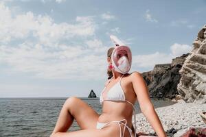 jong gelukkig vrouw in wit bikini en vervelend roze masker krijgt klaar voor zee snorkelen. positief glimlachen vrouw ontspannende en genieten van water activiteiten met familie zomer reizen vakantie vakantie Aan zee. foto