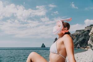 jong gelukkig vrouw in wit bikini en vervelend roze masker krijgt klaar voor zee snorkelen. positief glimlachen vrouw ontspannende en genieten van water activiteiten met familie zomer reizen vakantie vakantie Aan zee. foto