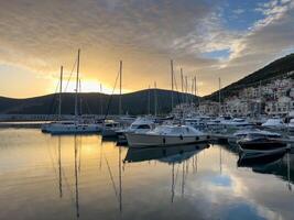 lustica, Montenegro - 15 augustus 2023. jachthaven met het zeilen jachten in de buurt de berg kust Bij zonsondergang foto