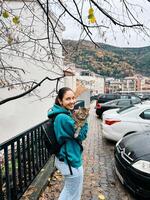 budva, Montenegro - 25 december 2022. glimlachen jong vrouw met een groot kat in haar armen staat in de buurt de huis Aan de straat foto