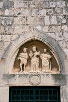 standbeelden van drie heiligen in een lunette bovenstaand de voorkant deur van de kerk van st. luk. dubrovnik, Kroatië foto