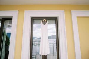 bruids jurk blijft hangen Aan een hanger Aan de hotel balkon deur foto