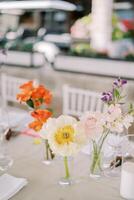 helder bloemen staan in glas vazen Aan een feestelijk tafel foto