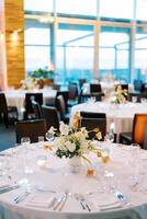 kleurrijk boeket van bloemen staat Aan een ronde tafel met lit kaarsen in kandelaars foto