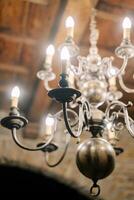 vertakt gloeiend kroonluchter met kaars lampen blijft hangen van een houten plafond foto